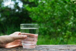 manos sosteniendo agua limpia con fondo verde